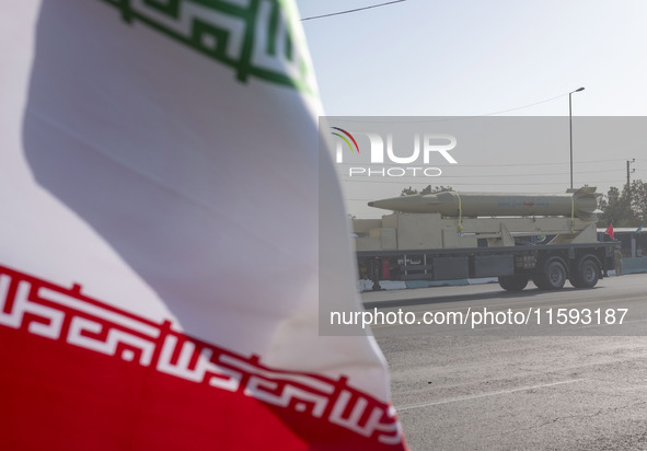 An Iran-made missile, Haj Qassem Soleimani, is carried past an Iranian flag by a truck during a military parade commemorating the anniversar...