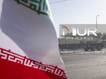 An Iran-made missile, Haj Qassem Soleimani, is carried past an Iranian flag by a truck during a military parade commemorating the anniversar...