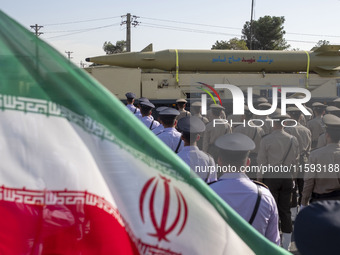 An Iran-made missile, Haj Qassem Soleimani, is carried past an Iranian flag by a truck during a military parade commemorating the anniversar...