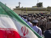 An Iran-made missile, Haj Qassem Soleimani, is carried past an Iranian flag by a truck during a military parade commemorating the anniversar...