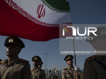 Members of the Iranian Army's land force stand at attention while one of them holds an Iranian flag during a military parade commemorating t...