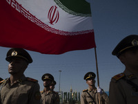 Members of the Iranian Army's land force stand at attention while one of them holds an Iranian flag during a military parade commemorating t...