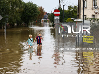 Children walk in the water after Nysa Klodzka river flooded town of Lewin Brzeski in southwestern Poland, on September 19th, 2024. Storm Bor...