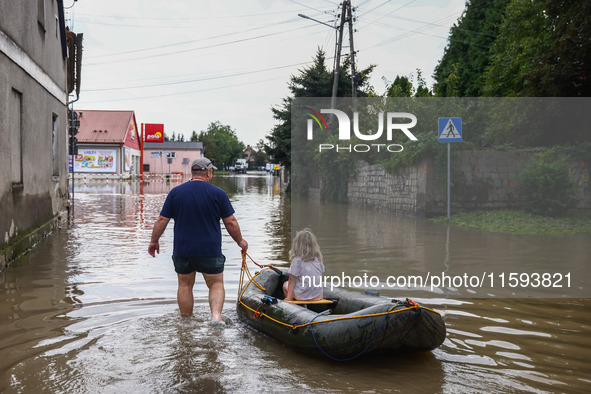 A man with a girl are seen with a raft after Nysa Klodzka river flooded town of Lewin Brzeski in southwestern Poland, on September 19th, 202...