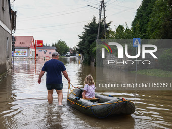 A man with a girl are seen with a raft after Nysa Klodzka river flooded town of Lewin Brzeski in southwestern Poland, on September 19th, 202...