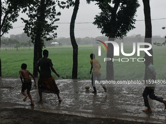 Bangladeshi children play football on a village street during light rain in Nandail, Bangladesh, on September 21, 2024. (