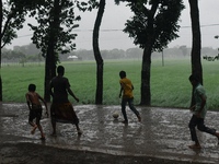 Bangladeshi children play football on a village street during light rain in Nandail, Bangladesh, on September 21, 2024. (