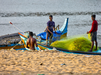 Fishermen untangle fishing nets along Paruthiyoor Beach in Paruthiyoor, Kerala, India, on April 15, 2024. (