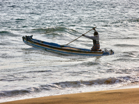 A fisherman paddles a fishing boat into the ocean along Paruthiyoor Beach in Paruthiyoor, Kerala, India, on April 15, 2024. (