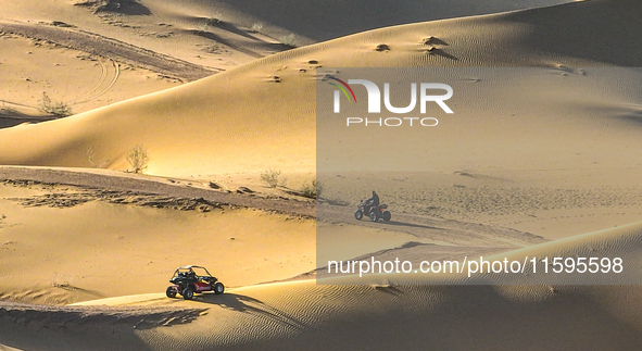 Tourists drive desert motorcycles through the Badain Jaran Desert at the Jinshawan Desert Tourism holiday camp in Zhangye, China, on Septemb...