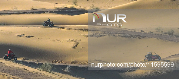 Tourists drive desert motorcycles through the Badain Jaran Desert at the Jinshawan Desert Tourism holiday camp in Zhangye, China, on Septemb...