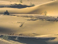 Tourists drive desert motorcycles through the Badain Jaran Desert at the Jinshawan Desert Tourism holiday camp in Zhangye, China, on Septemb...