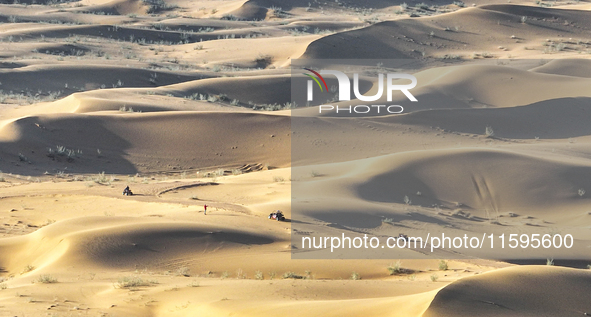 Tourists drive desert motorcycles through the Badain Jaran Desert at the Jinshawan Desert Tourism holiday camp in Zhangye, China, on Septemb...