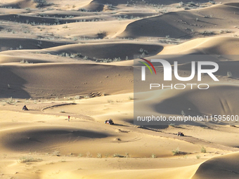 Tourists drive desert motorcycles through the Badain Jaran Desert at the Jinshawan Desert Tourism holiday camp in Zhangye, China, on Septemb...