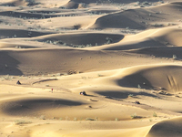 Tourists drive desert motorcycles through the Badain Jaran Desert at the Jinshawan Desert Tourism holiday camp in Zhangye, China, on Septemb...