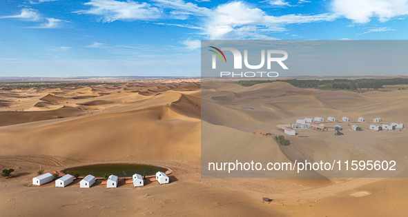 Tourists walk through the desert scenery at Jinshawan Desert tourism holiday camp in Zhangye, China, on September 21, 2024. 