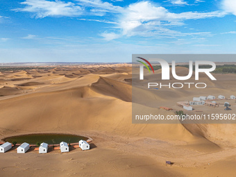 Tourists walk through the desert scenery at Jinshawan Desert tourism holiday camp in Zhangye, China, on September 21, 2024. (