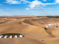 Tourists walk through the desert scenery at Jinshawan Desert tourism holiday camp in Zhangye, China, on September 21, 2024. (