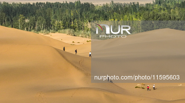 Tourists climb the sand peak to view the scenery of the desert oasis at Jinshawan Desert tourism holiday camp in Zhangye, China, on Septembe...