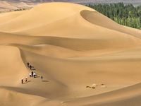 Tourists climb the sand peak to view the scenery of the desert oasis at Jinshawan Desert tourism holiday camp in Zhangye, China, on Septembe...