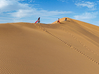 Tourists climb the sand peak to prepare for sand skating at the Jinshawan Desert tourism holiday camp in Zhangye, China, on September 21, 20...