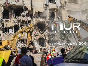 Rescuers sift through the rubble at the scene of an Israeli strike that targets Beirut's southern suburbs, as search and rescue operations c...