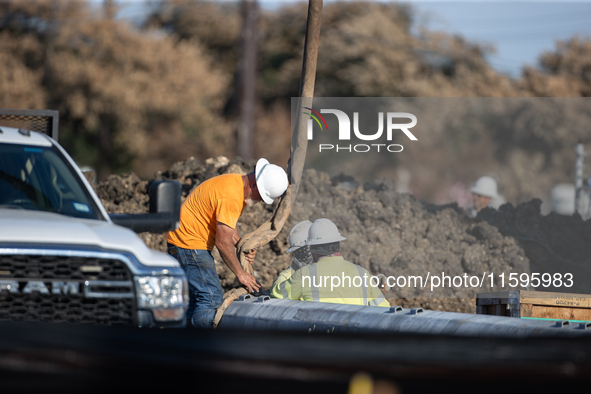 Workers repair a damaged liquefied gas pipeline following an explosion earlier in the week in La Porte, near Houston, Texas, on September 21...