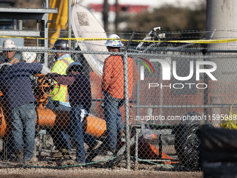 Workers repair a damaged liquefied gas pipeline following an explosion earlier in the week in La Porte, near Houston, Texas, on September 21...