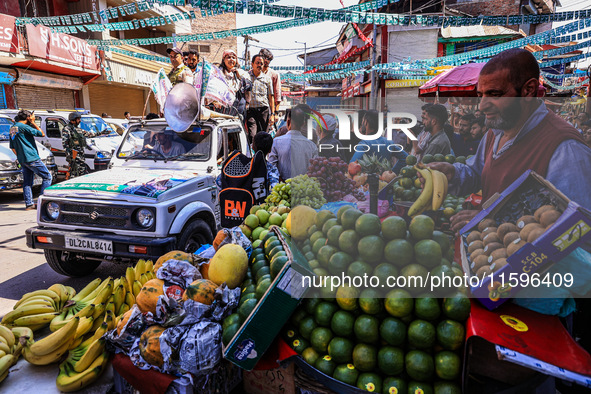 A vendor sells fruits as Kashmiri Pandit woman and Independent candidate for Sopore Assembly Constituency, Aarti Nehru, campaigns in Sopore,...