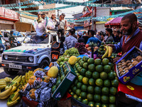 A vendor sells fruits as Kashmiri Pandit woman and Independent candidate for Sopore Assembly Constituency, Aarti Nehru, campaigns in Sopore,...