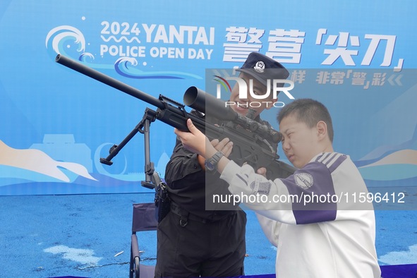 A child handles police firearms at the Open Day of a police camp in Yantai, China, on September 21, 2024. 