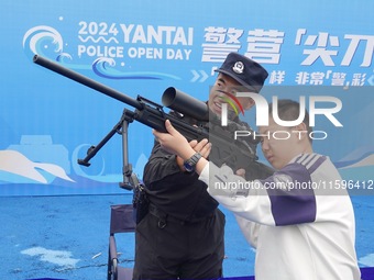 A child handles police firearms at the Open Day of a police camp in Yantai, China, on September 21, 2024. (