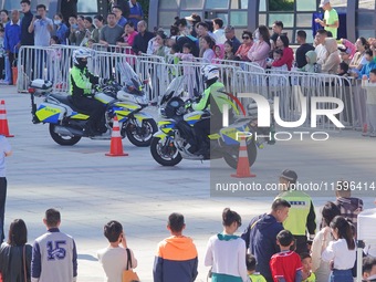 Traffic policemen demonstrate their driving skills on a police motorcycle during the Open Day of the police camp of Yantai Public Security B...