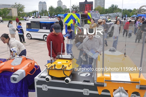 Citizens look at new intelligent police equipment at the Open Day of the police camp of Yantai Public Security Bureau in Yantai, China, on S...