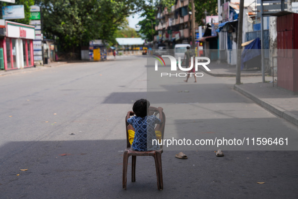 A kid sits on a chair on an empty street in Colombo, Sri Lanka, on September 22, 2024. A curfew is imposed in Sri Lanka amid the counting of...