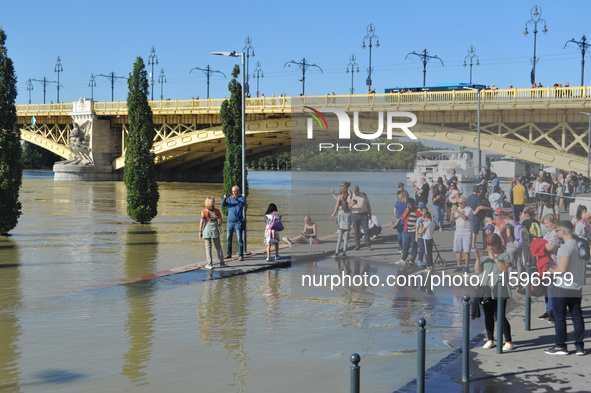 People take photos on the bank of the Danube in Budapest, Hungary, as the peak water levels of the Danube are expected to hit today. 