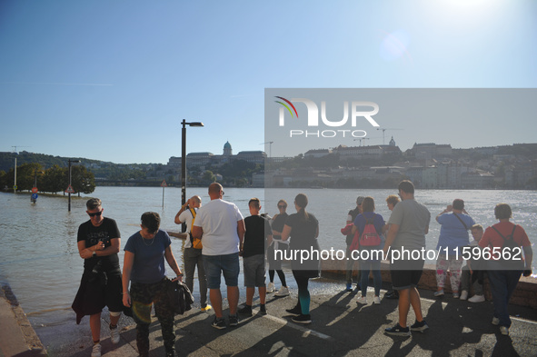 People look at the flooded quay on the bank of the Danube in Budapest, Hungary, as the peak water levels of the Danube are expected to hit t...