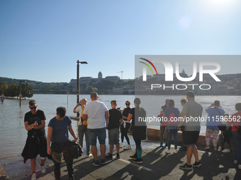 People look at the flooded quay on the bank of the Danube in Budapest, Hungary, as the peak water levels of the Danube are expected to hit t...