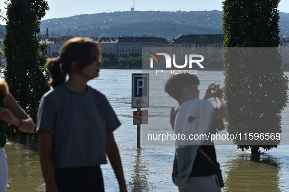 People look at the flooded quay on the bank of the Danube in Budapest, Hungary, on Month Day, Year, as the peak water levels of the Danube a...