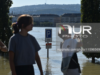 People look at the flooded quay on the bank of the Danube in Budapest, Hungary, on Month Day, Year, as the peak water levels of the Danube a...