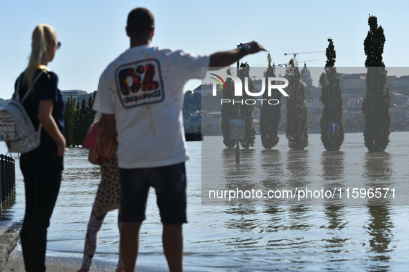 People look at the flooded quay on the bank of the Danube in Budapest, Hungary, on Month Day, Year, as the peak water levels of the Danube a...