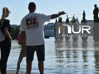 People look at the flooded quay on the bank of the Danube in Budapest, Hungary, on Month Day, Year, as the peak water levels of the Danube a...