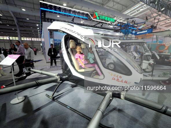 A child experiences an electric unmanned aircraft at the 16th International Transportation Technology and Equipment Exhibition in Beijing, C...