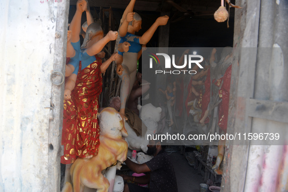 Male and female artists work on a semi-finished idol of the Hindu goddess 'Durga' in Siliguri, India, on September 22, 2024. 