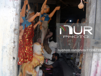 Male and female artists work on a semi-finished idol of the Hindu goddess 'Durga' in Siliguri, India, on September 22, 2024. (