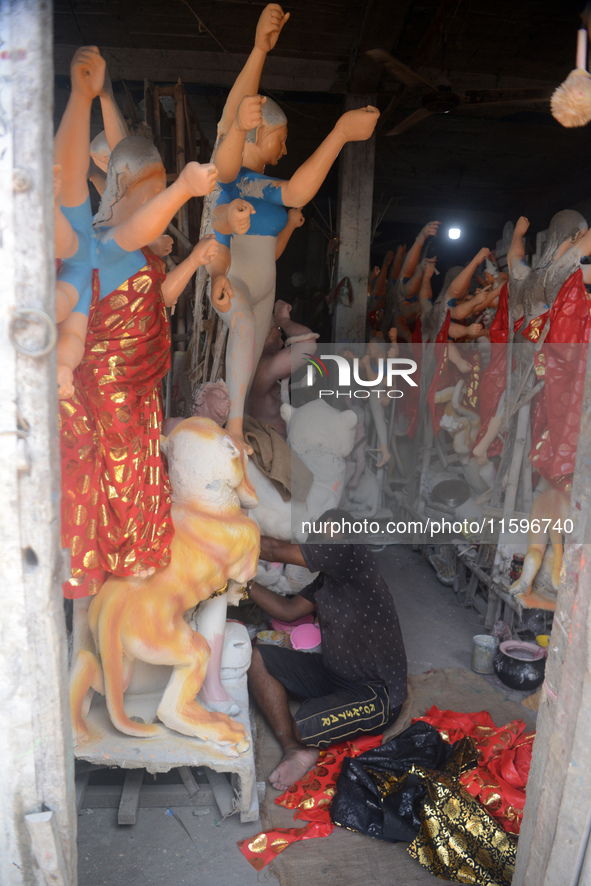 Male and female artists work on a semi-finished idol of the Hindu goddess 'Durga' in Siliguri, India, on September 22, 2024. 