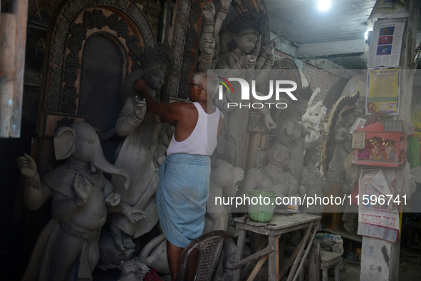 Male and female artists work on a semi-finished idol of the Hindu goddess 'Durga' in Siliguri, India, on September 22, 2024. 