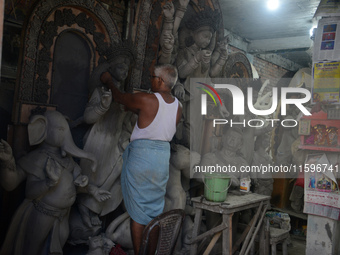 Male and female artists work on a semi-finished idol of the Hindu goddess 'Durga' in Siliguri, India, on September 22, 2024. (