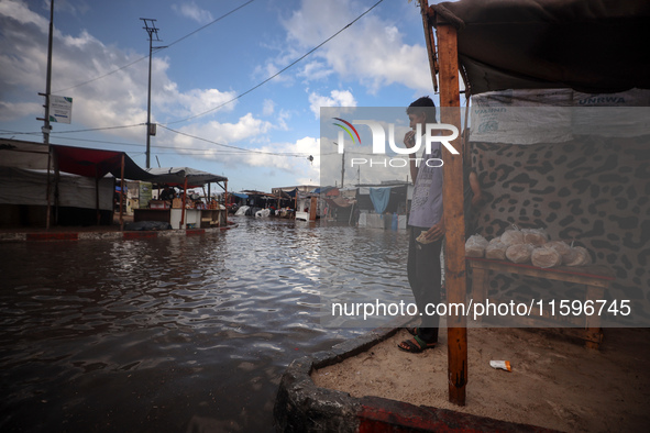 A Palestinian boy walks in a puddle in rainy weather at a camp for displaced people in Khan Yunis, Gaza Strip, on September 22, 2024, amid t...