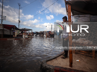 A Palestinian boy walks in a puddle in rainy weather at a camp for displaced people in Khan Yunis, Gaza Strip, on September 22, 2024, amid t...